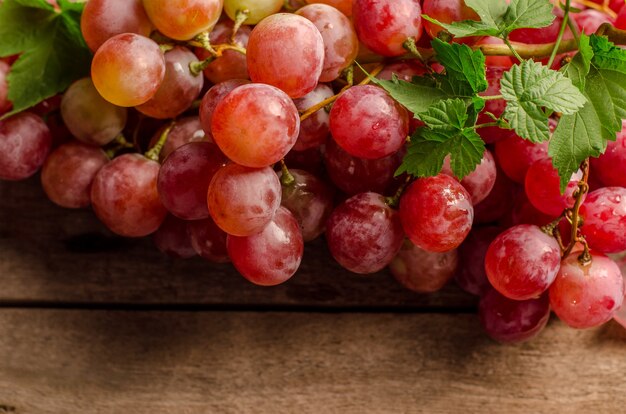 Uva rosa madura fresca em um prato vintage em um velho fundo de madeira