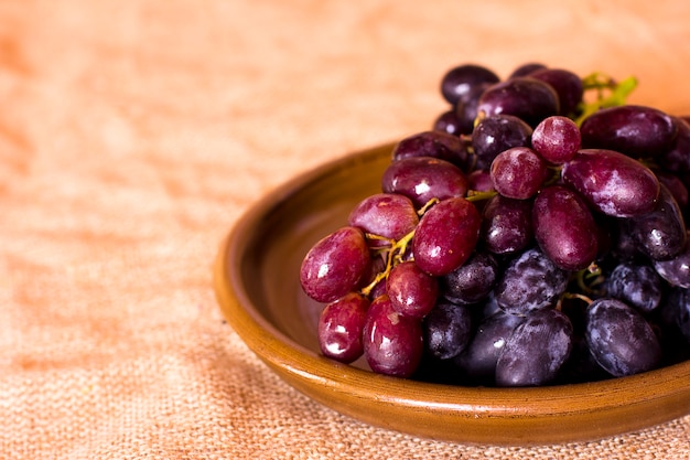 Foto uvas azules en un plato de arcilla marrón