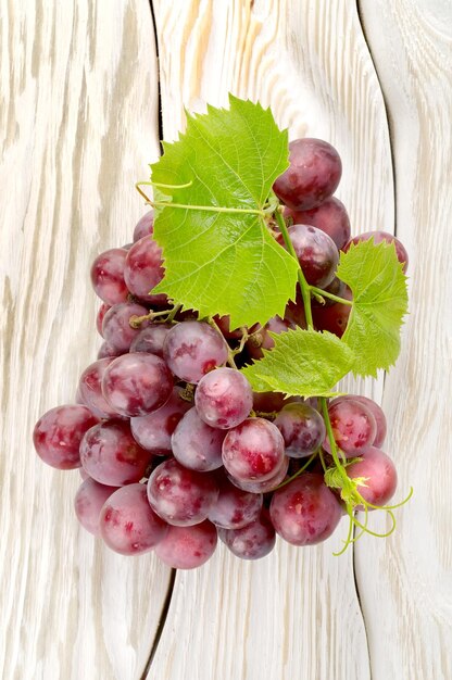 Uvas azules sobre un fondo de madera blanca