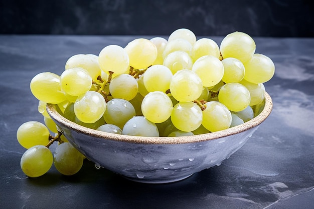 Uvas blancas en un cuenco sobre un fondo de mármol azul oscuro