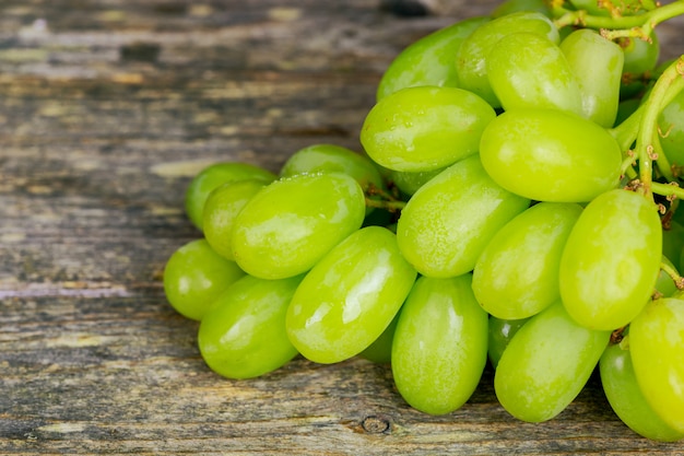 Uvas blancas macro. Uvas con gotas de agua. Uvas y corcho. Uvas sobre fondo de madera