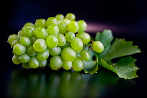 Uvas blancas selectivas con una hoja sobre un fondo oscuro