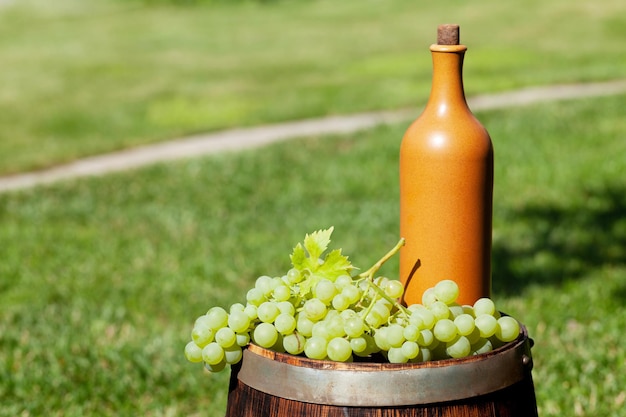 Uvas y botella de vino en tonel de vino