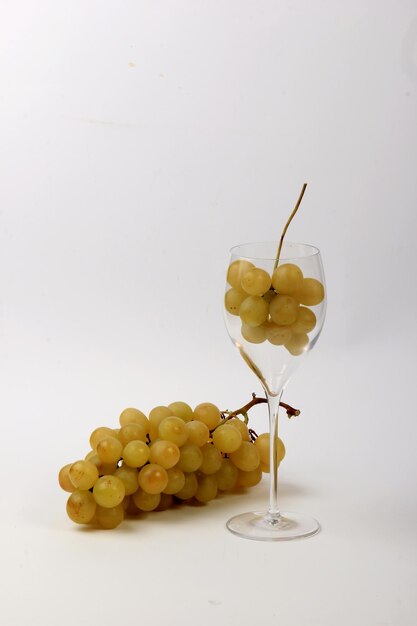 Uvas brancas em copos de vinho de vidro, fundo branco