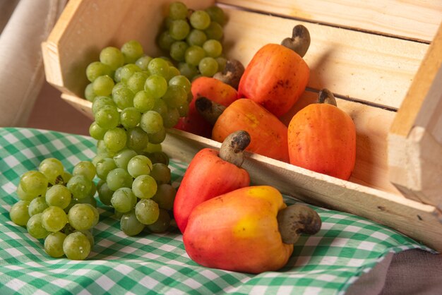 Uvas en una caja de madera y anacardos con telas en el fondo, poca profundidad de campo.