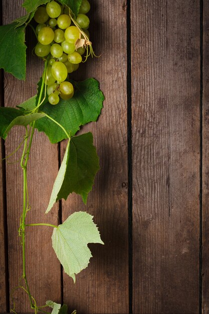Uvas com folhas no fundo de madeira closeup