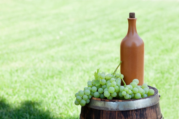 Uvas e garrafa de vinho no barril de vinho