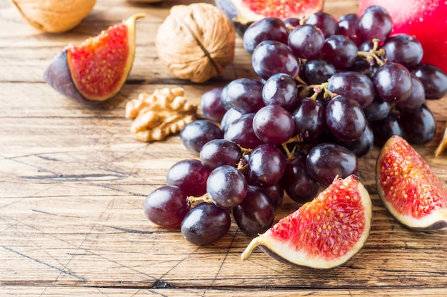 Uvas e higos negros con las nueces en una tabla de madera con una copia del espacio.