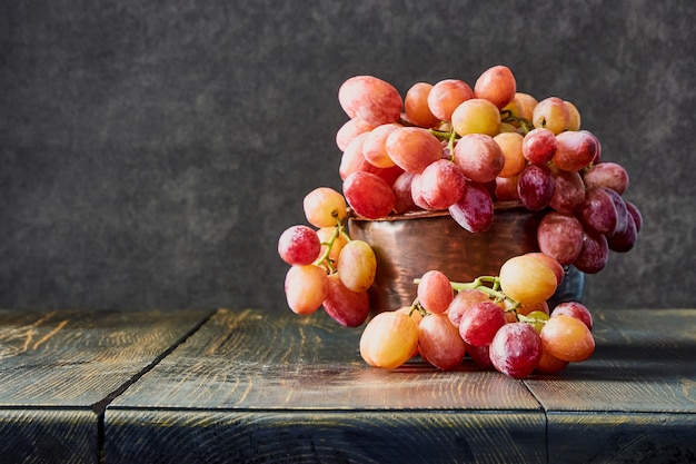 Foto uvas frescas. cachos de diferentes variedades em um prato sobre uma velha mesa de madeira