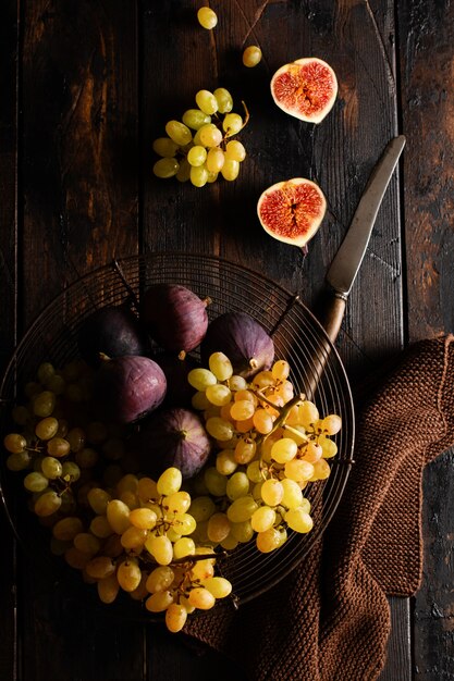 Uvas frescas e figos numa velha superfície de madeira em estilo retro. Vista do topo.