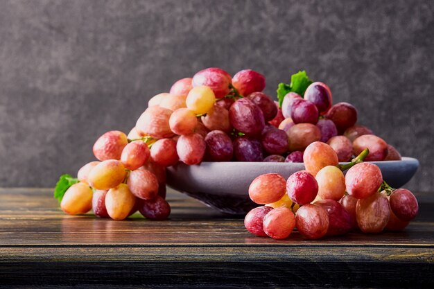 Uvas frescas. Racimos de diferentes variedades en un plato sobre una mesa de madera antigua