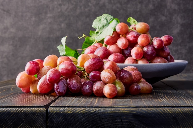 Uvas frescas. Racimos de diferentes variedades en un plato sobre una mesa de madera antigua