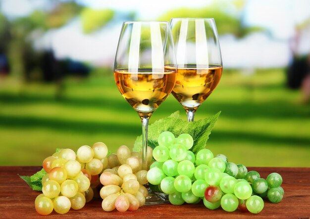 Uvas maduras y copas de vino sobre fondo brillante