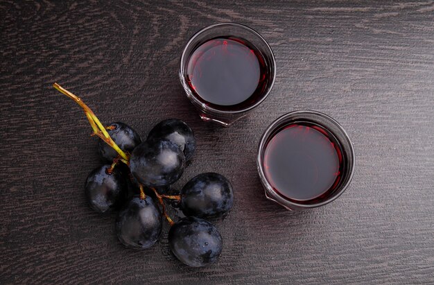 Uvas maduras, vinho tinto e um copo em um fundo preto