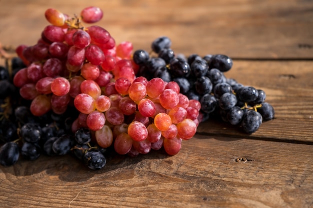 Uvas en una mesa de madera Rama fresca de uvas rojas con hojas