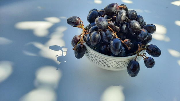 Uvas moradas en un recipiente con tallo aislado sobre fondo blanco y sombra 03