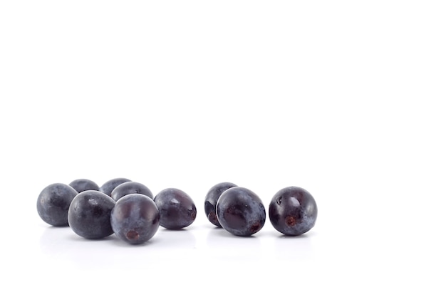 Uvas negras frescas en blanco