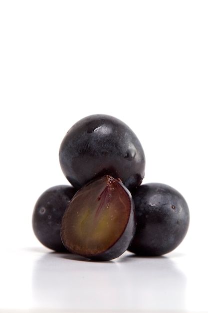 Uvas negras frescas en blanco