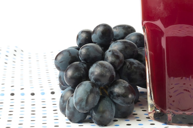 Uvas oscuras aisladas sobre fondo blanco vaso de jugo