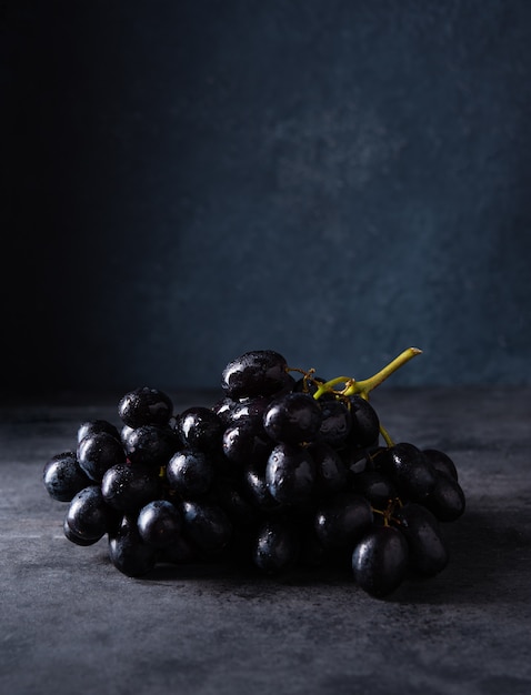 Uvas pretas suculentas em uma mesa escura