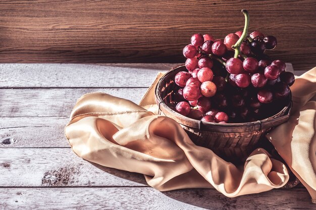 Uvas rojas en la cesta en la mesa de madera. Espacio libre para texto