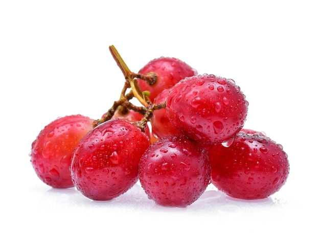 Uvas rojas y gotas de agua aisladas sobre fondo blanco.