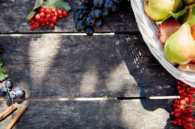 Uvas rústicas de outono, peras, viburno e paus de canela com sombras da moda Decorações de mesa de madeira de outono Conceito de dia de ação de graças Fundo de outono ao ar livre