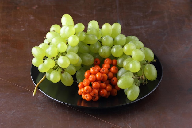 Uvas suculentas maduras e sorvas em uma placa preta sobre fundo escuro Colheita de frutas cruas e orgânicas do jardim fechado