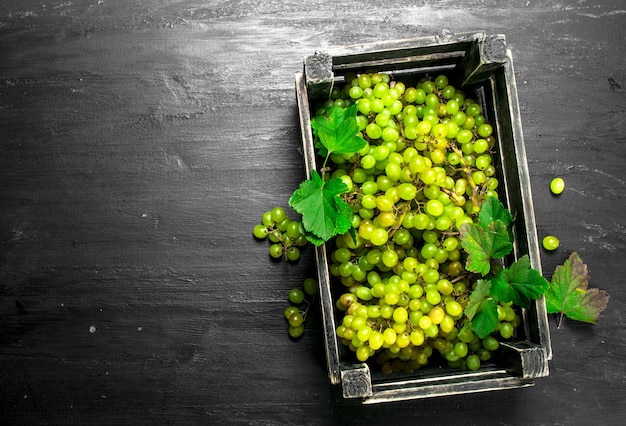 Uvas verdes en una caja. En la pizarra negra.