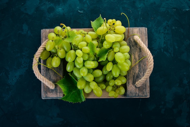 Uvas verdes com folhas de uvas em uma mesa de pedra Vista superior Espaço livre para texto