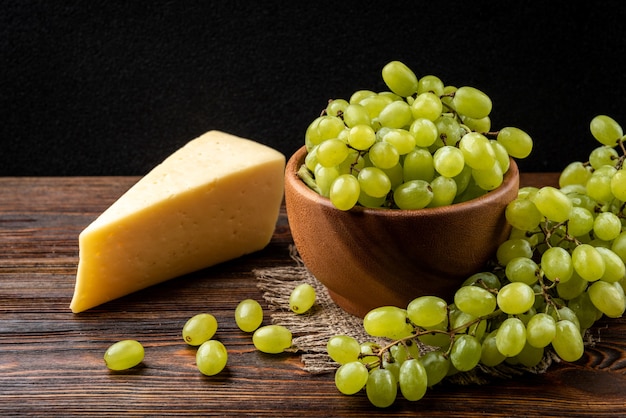 Uvas verdes com queijo em uma tigela de madeira sobre a mesa