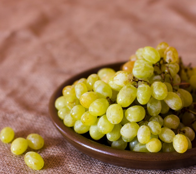 Uvas verdes em um prato de barro marrom