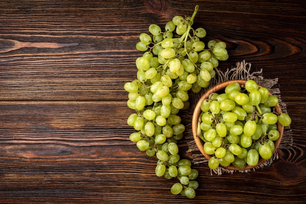 Uvas verdes em uma tigela de madeira sobre a mesa