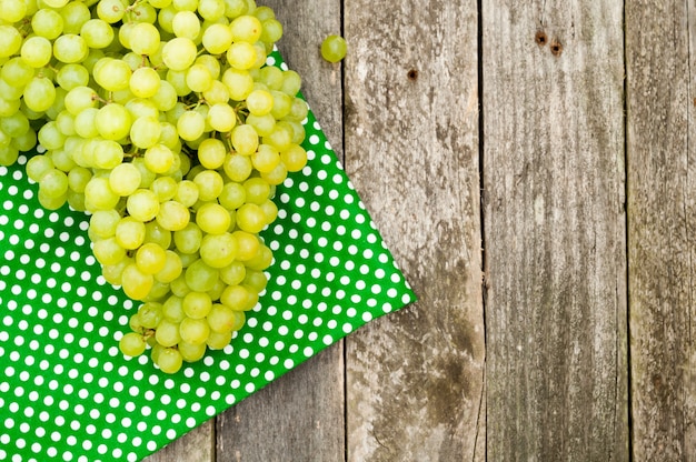 Uvas verdes frescas e guardanapo de tecido em fundo de madeira velho