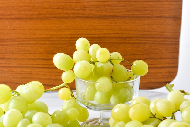 Uvas verdes frescas em um copo de sorvete com fundo de madeira marrom