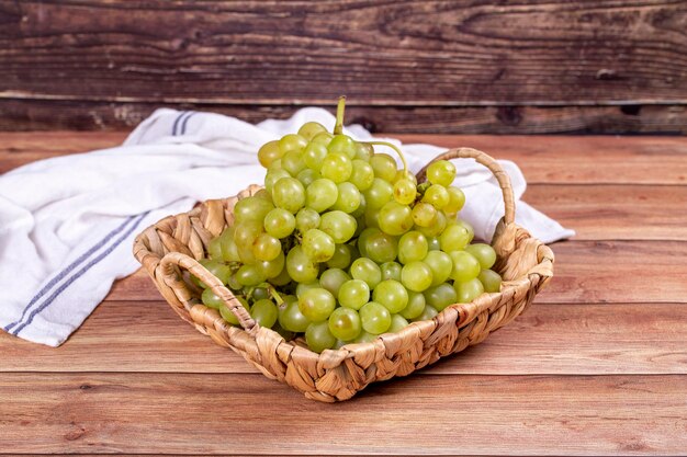 Uvas verdes frescas Uvas maduras en canasta sobre fondo de madera Uvas a granel de cerca