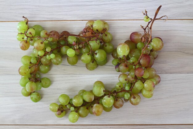 Uvas verdes con hojas sobre un fondo de madera antiguo. Vista superior. Espacio de copia.