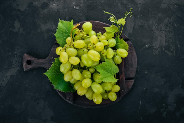 Uvas verdes con hojas de uvas en una mesa de piedra Vista superior Espacio libre para texto