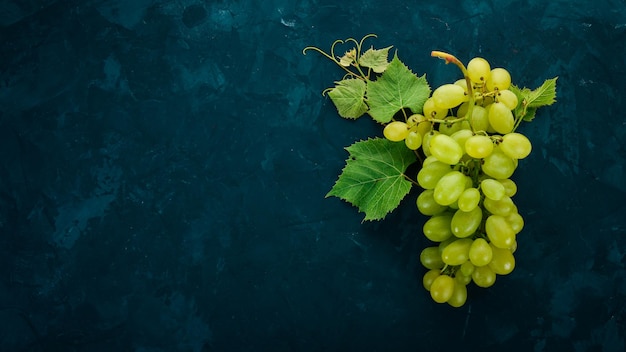 Uvas verdes con hojas de uvas en una mesa de piedra Vista superior Espacio libre para texto