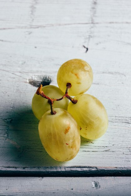 Uvas verdes maduras em fundo de madeira clara Espaço de cópia