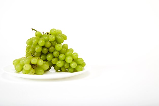 Uvas verdes maduras en una placa blanca.