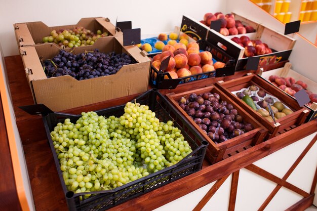 Uvas verdes y otras frutas en una caja en el mostrador de una tienda de verduras.