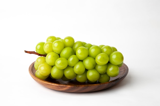 Uvas verdes en una placa de madera