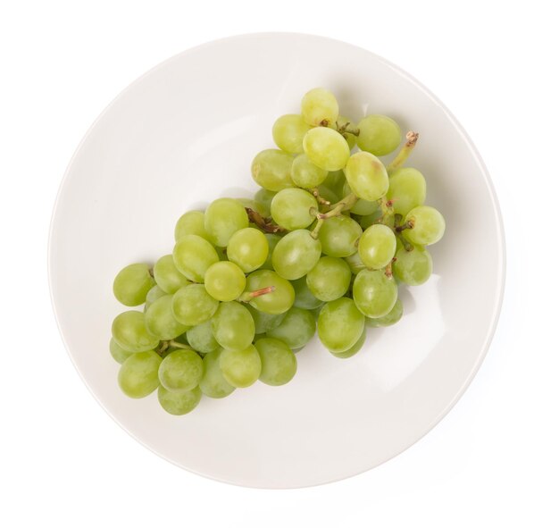 Uvas verdes en plato aislado sobre fondo blanco.