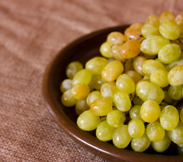 Uvas verdes en un plato de arcilla marrón