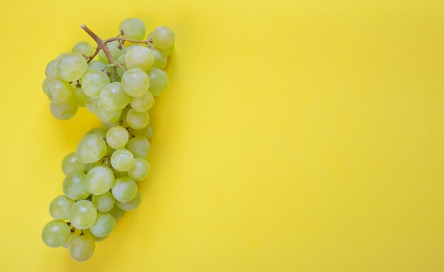 Uvas verdes sobre fondo amarillo con espacio de copia.