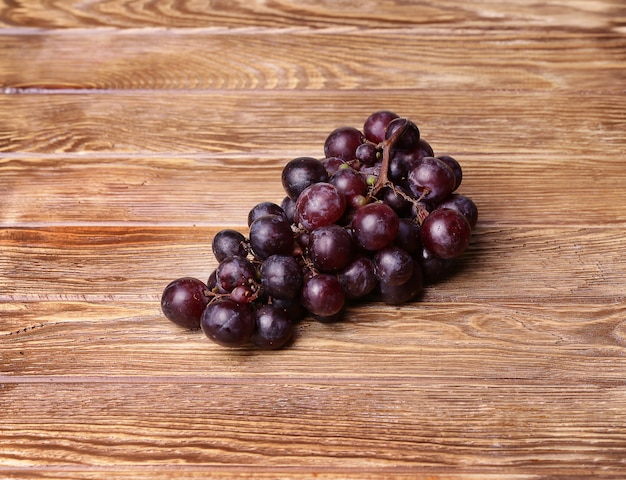 Uvas vermelhas em fundo de mesa de madeira