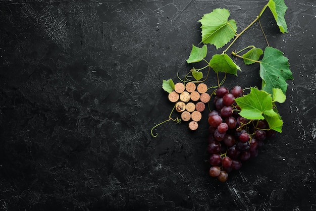 Uvas vermelhas frescas com folhas em uma mesa de pedra preta Vista superior Espaço livre para o seu texto