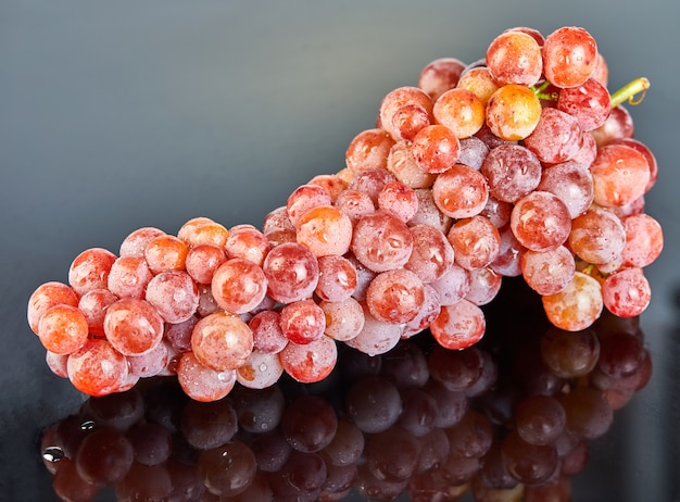 Uvas vermelhas frescas com gotas de água no fundo cinza