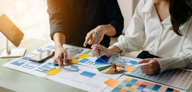 UX-Entwickler und UI-Designer beim Brainstorming über das Wireframe-Design der mobilen App-Schnittstelle mit Kundeninformationen und Farbcode bei officexA